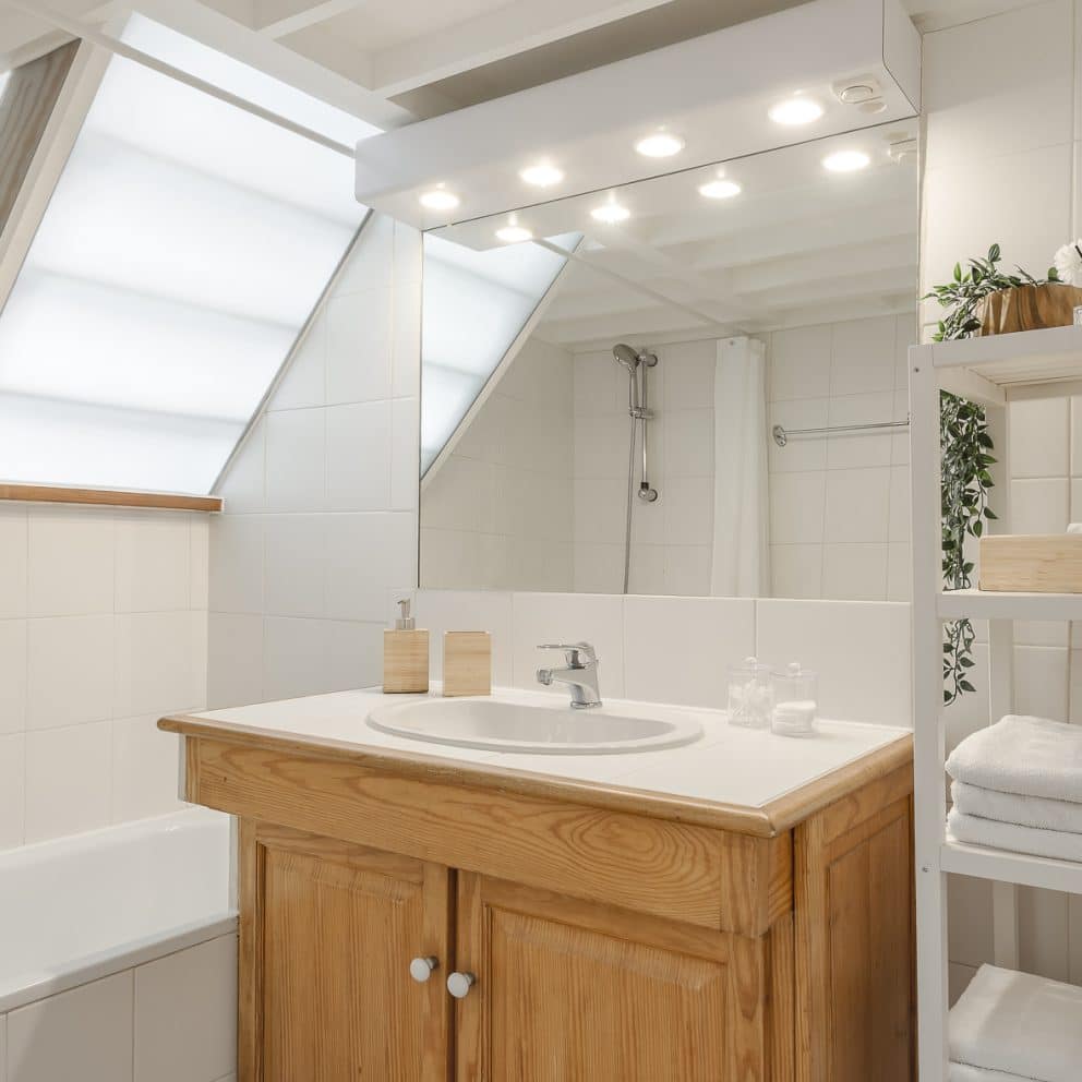 Salle de bain avec baignoire, meuble vasque en bois et étagère de serviettes, dans l'appartement L'Authentique à Aix-en-Provence