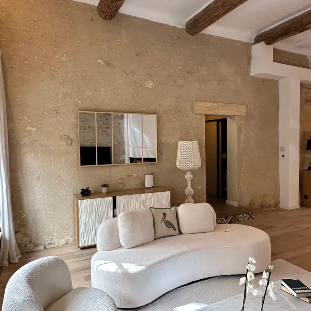 Salon spacieux avec murs en pierre apparente et canapés design blancs dans un triplex de luxe à Aix-en-Provence.