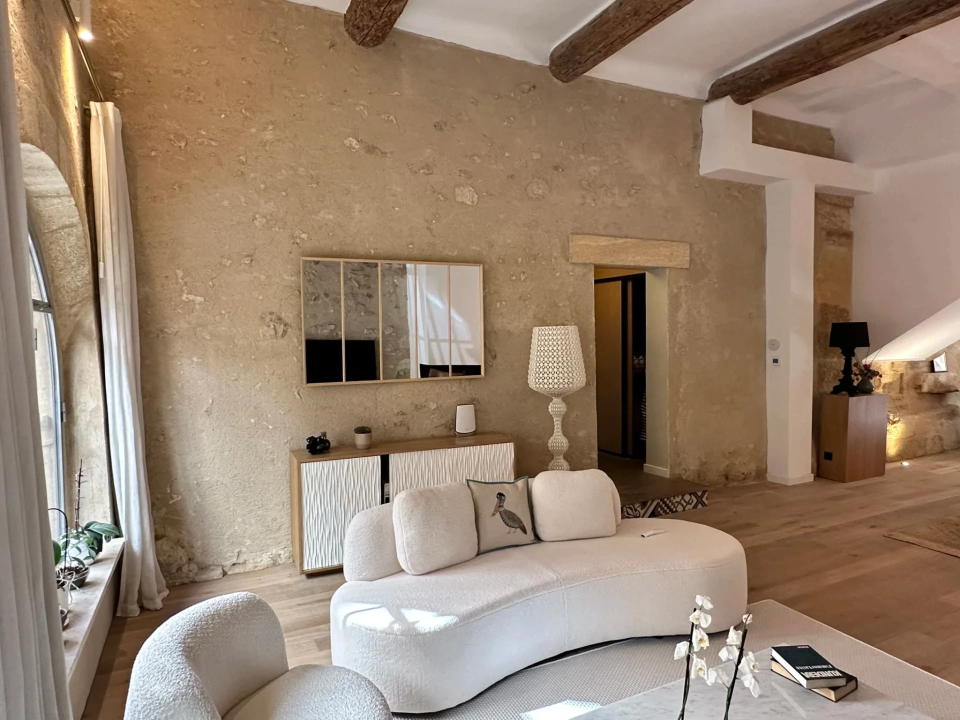 Salon spacieux avec murs en pierre apparente et canapés design blancs dans un triplex de luxe à Aix-en-Provence.